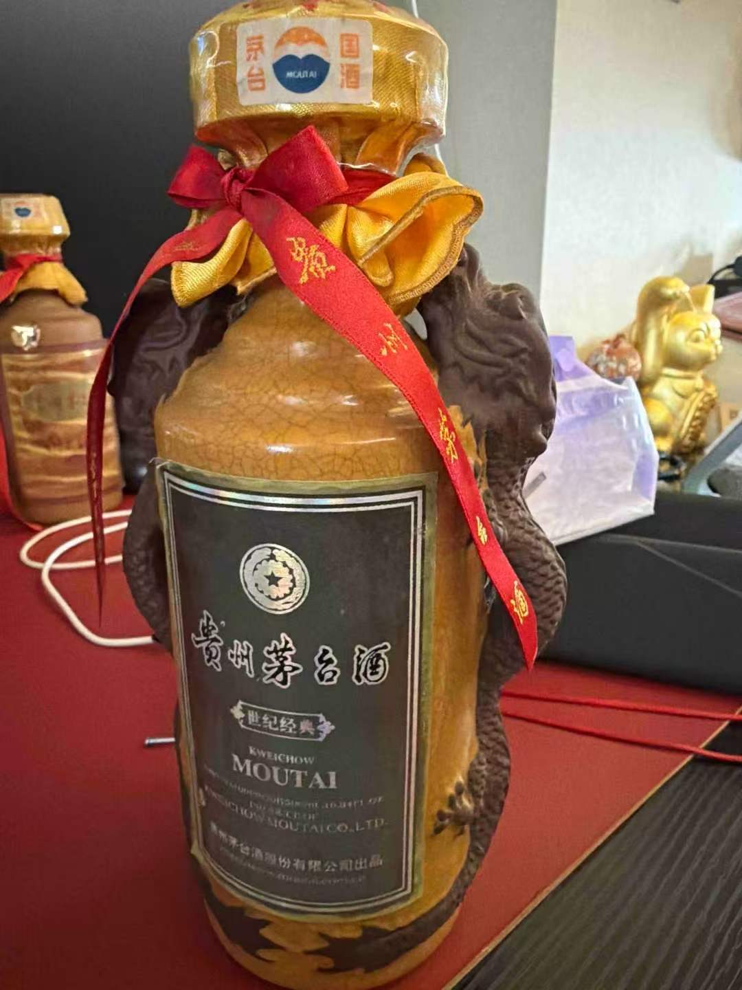 瓶身标签可见世纪经典,配红色飘带及棕黄色装饰瓶体